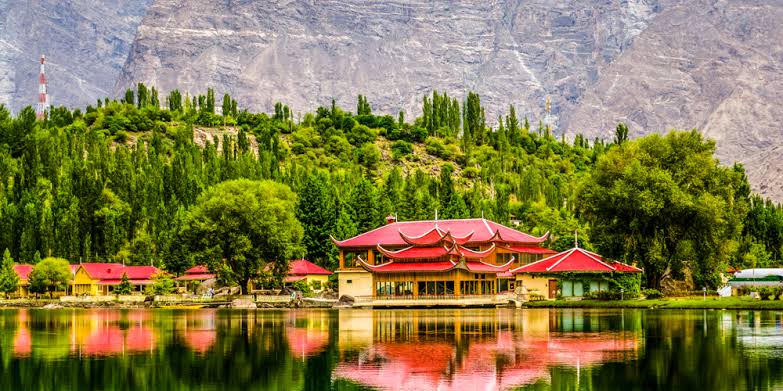Timber resort buildings surrounding the green waters of Lower Kachura lake at dawn
